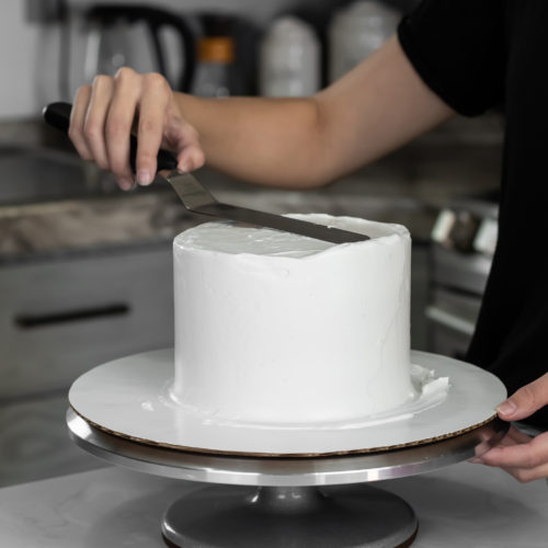 smoothing whipped cream cake with offset spatula